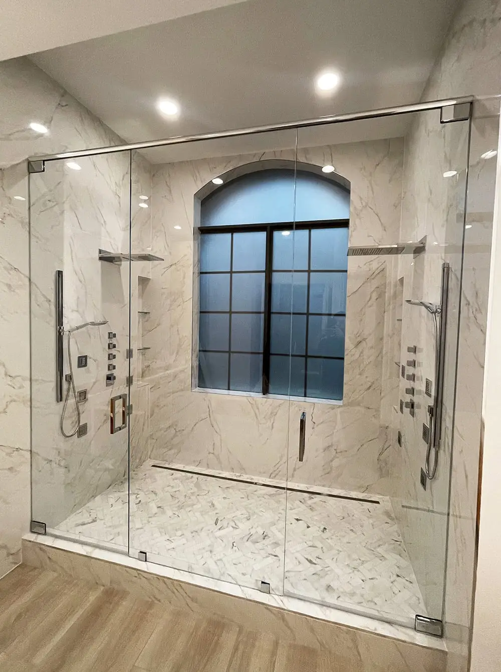 Wide inline shower enclosure with two swing glass doors and a fixed center panel