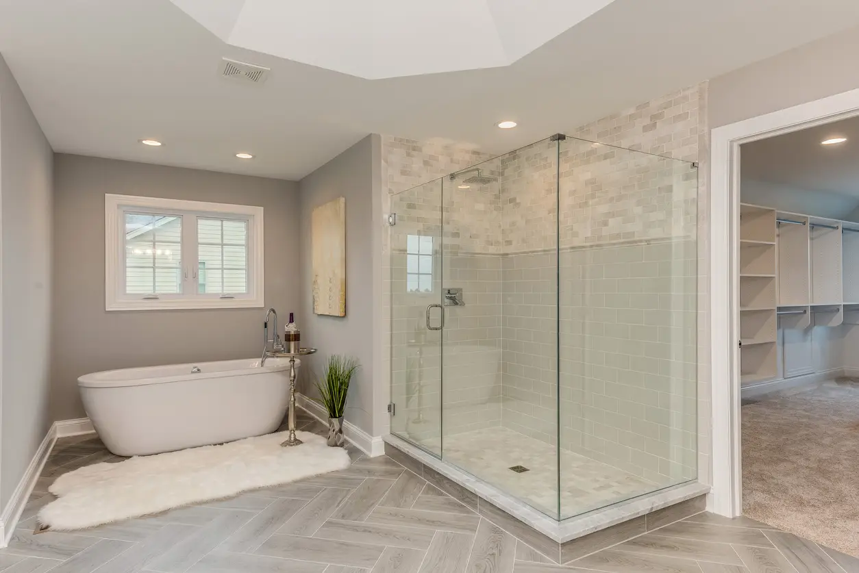 Walk-in shower with a single fixed glass panel returning at 90 degrees, white subway tile, and pebble accent.